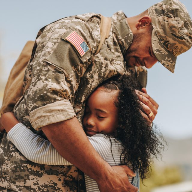 Emotional soldier saying his goodbye to his daughter before going to war. Patriotic serviceman embracing his child before leaving to go serve his country in the military.